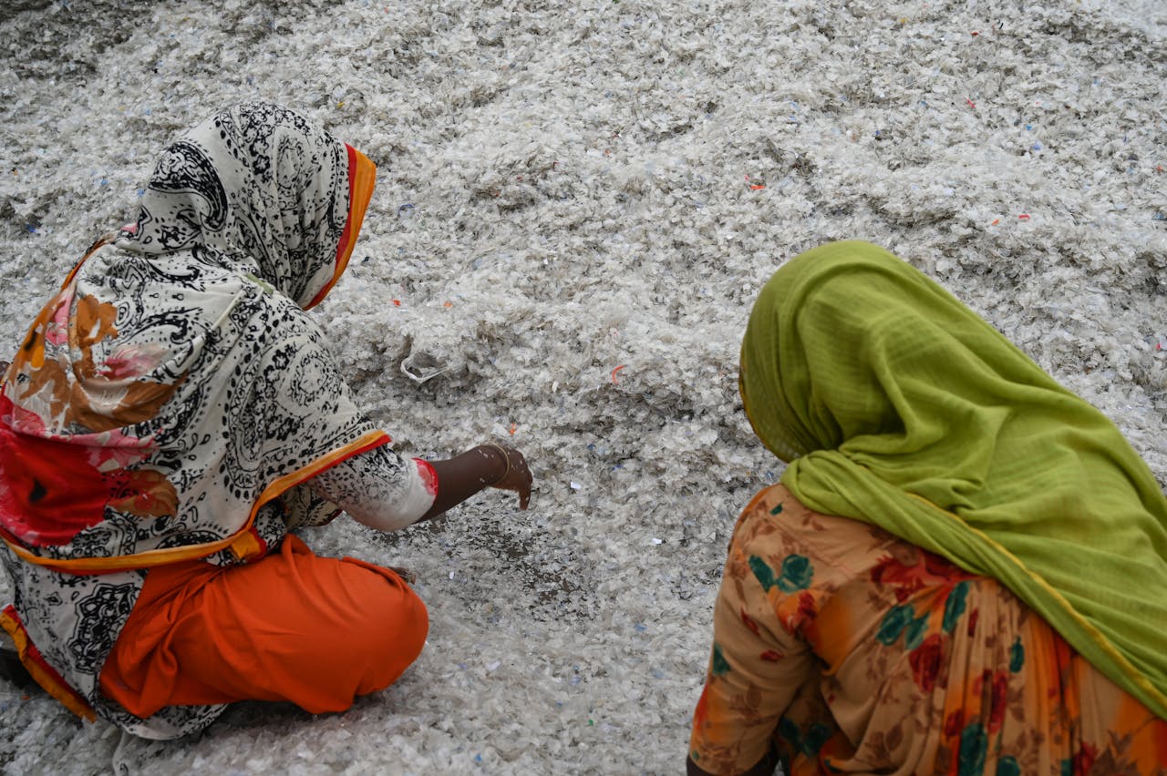 Two women sorting through shredded plastic for recycling in Chattogram, Bangladesh.
